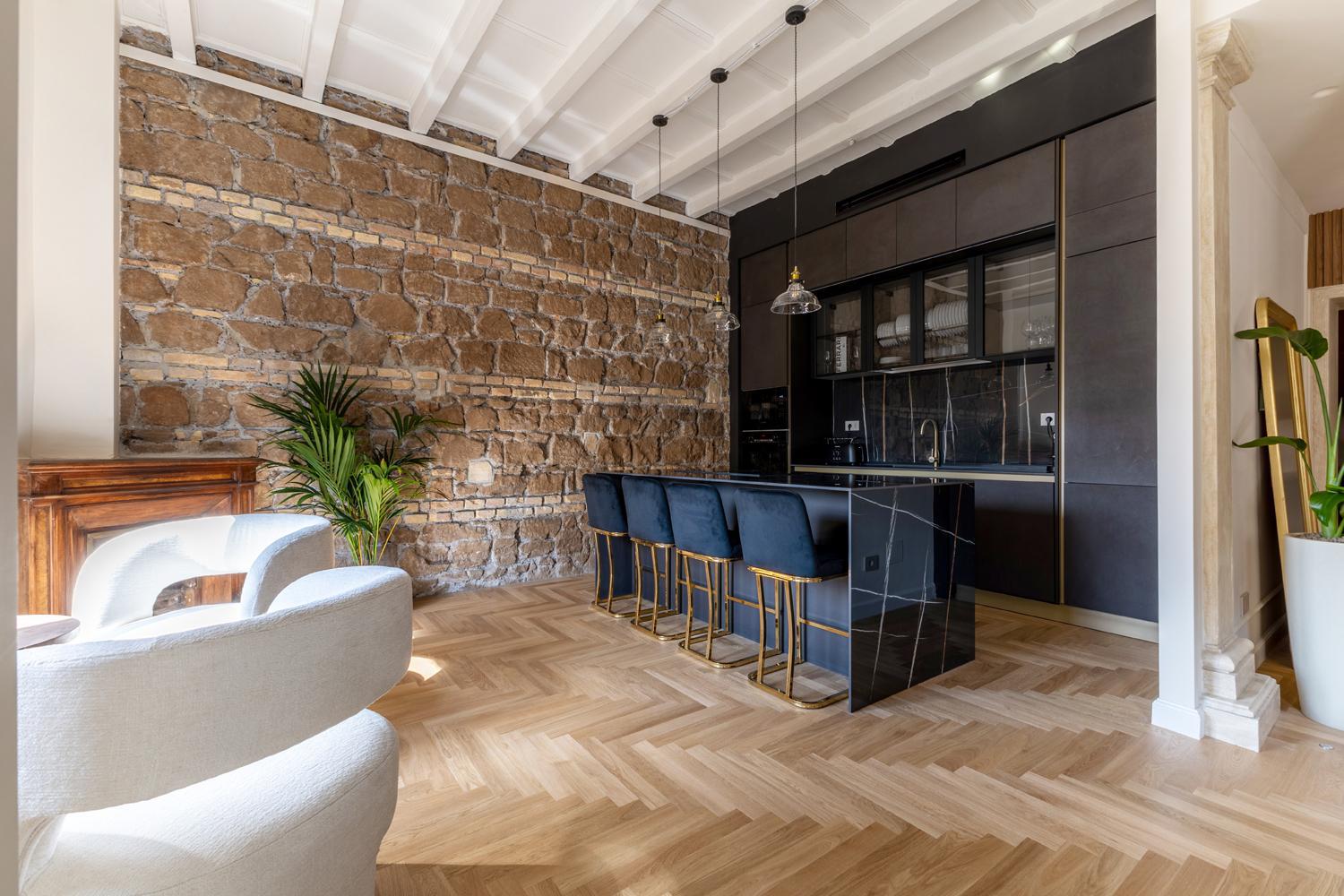 Cucina con isola in marmo e parete grezza — ristrutturazione cucina a Roma · HOME360